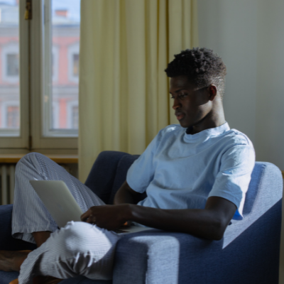 Black boy using laptop on a chair 